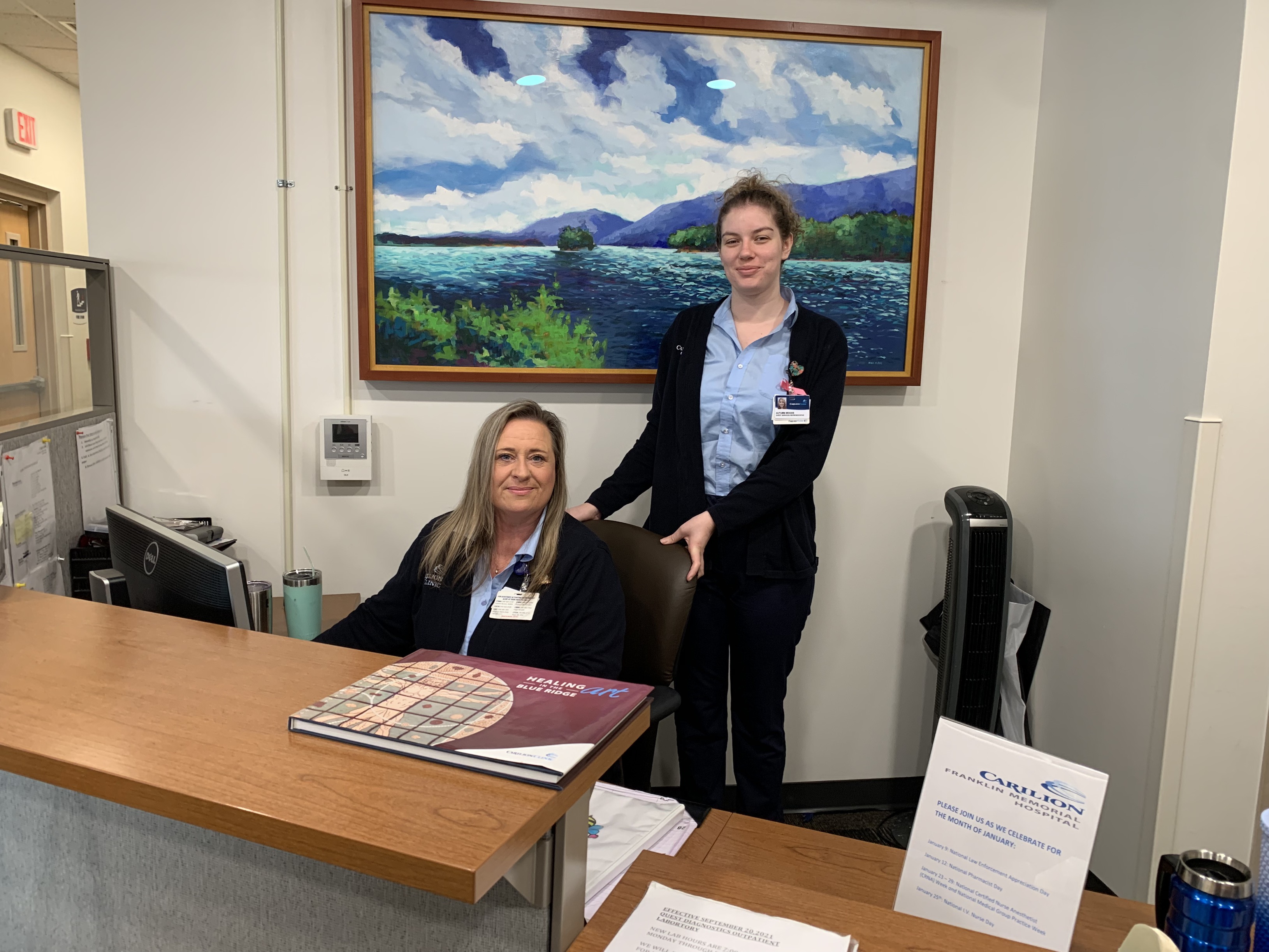 Volunteers at desk smiling and looking at camera