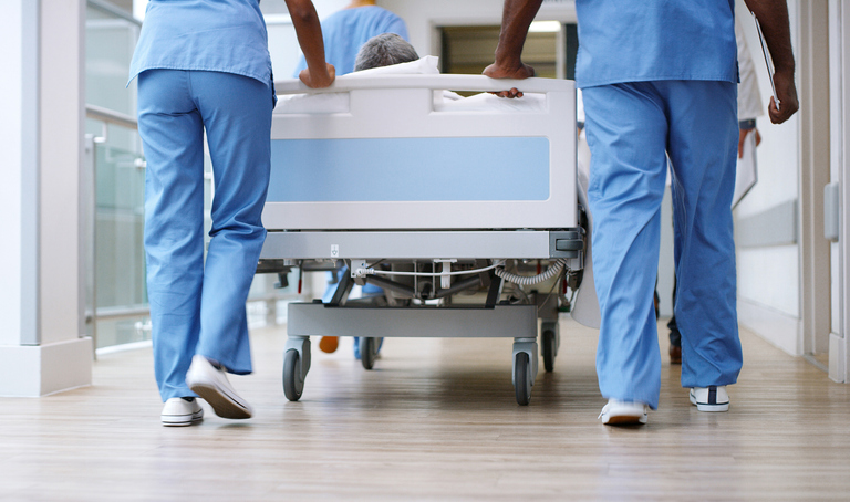 a patient in a hospital bed being rolled down the hall by nurses