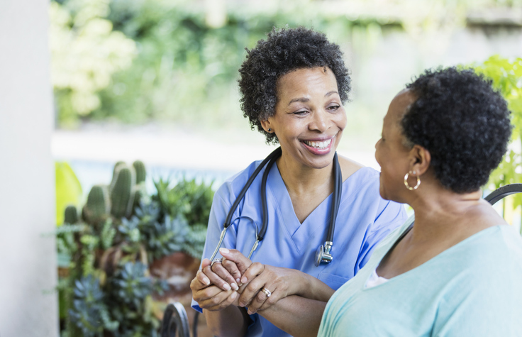 a nurse sitting with a patient smiling