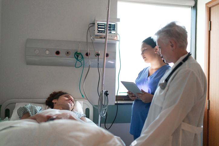 doctors talking to a patient in a hospital bed