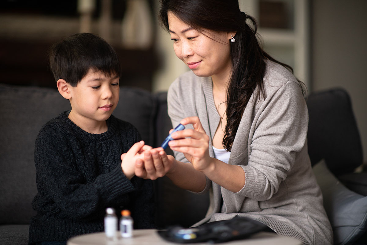Mother helping son check blood sugar levels