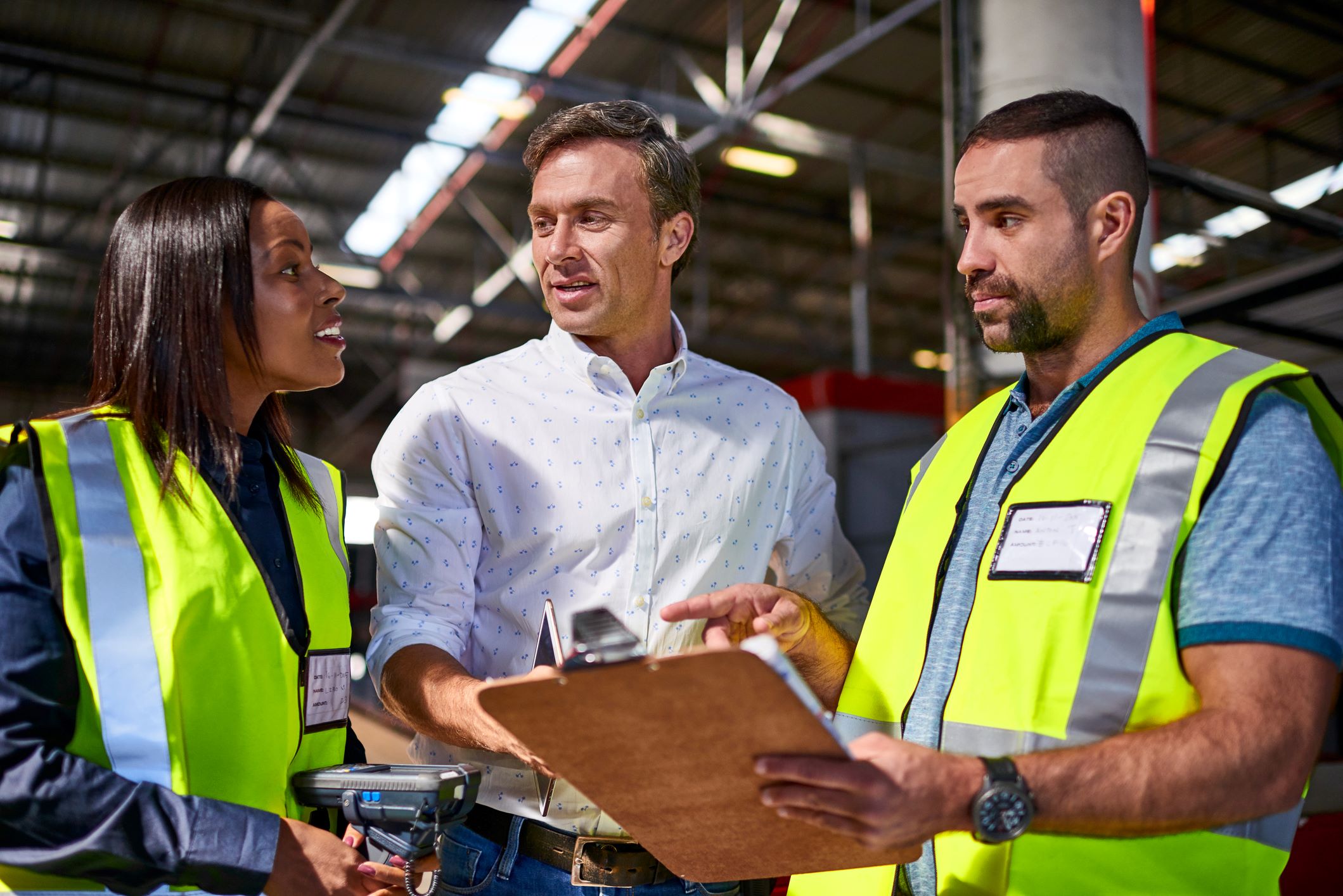 Workers in warehouse talking over clipboard image