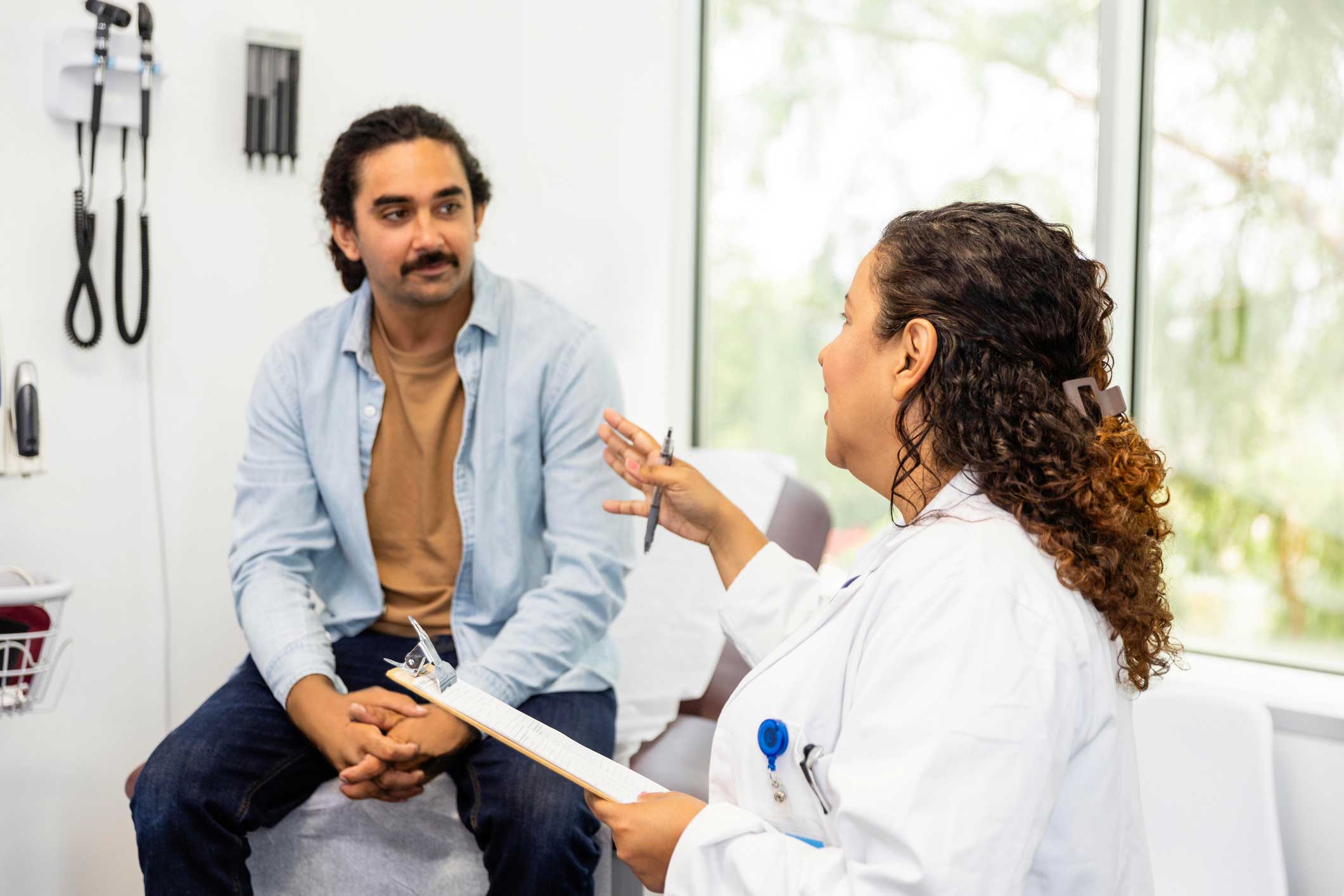 Man sitting on an exam table speaking with a doctor